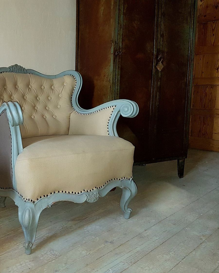 Due vecchie poltrone imbottite, con lo schienale capitonné, su un pavimento di legno