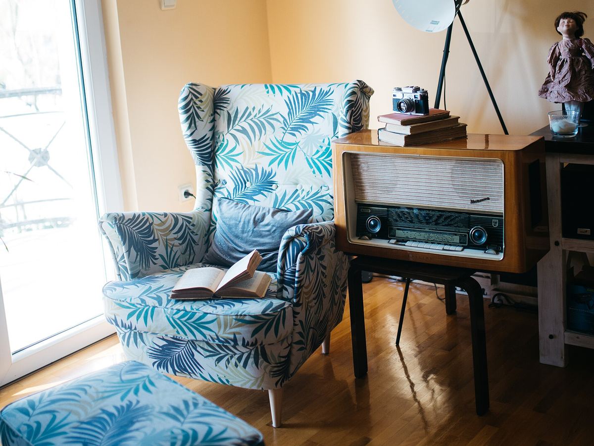 Una poltrona, una radio d'epoca e una lampada in un angolo di casa